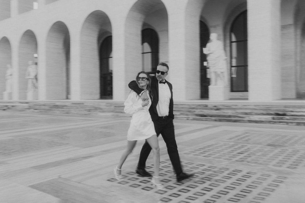 Wedding couple walking in front of minimalism architecture in Rome